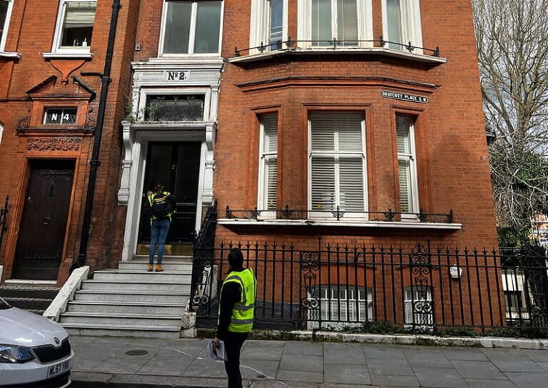 Damp surveyors in reflective vests assessing a property entrance at number 2 on a residential street in London, highlighting expertise in moisture damage prevention.