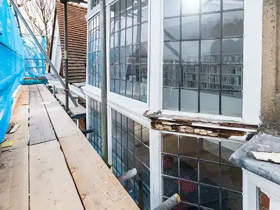 Sash window restoration project showing wooden windows with visible damage and scaffolding, emphasizing the delicate repair process for period homes.