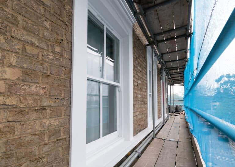 Georgian house restoration featuring newly installed sash windows and scaffolding, showcasing craftsmanship and attention to detail in the renovation process.