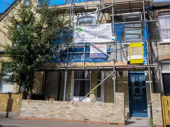 Scaffolded communal property undergoing restoration with Environ Restoration Services banner, showcasing expertise in Section 20 works in London.
