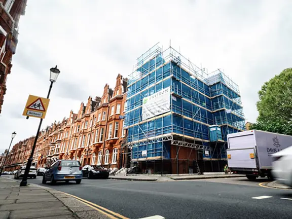 Building under restoration with scaffolding and protective sheeting in a London street, showcasing communal property maintenance related to Section 20 works.