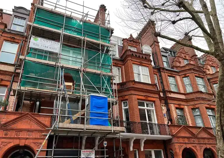 Victorian house restoration in progress, featuring scaffolding, green protective sheeting, and the Environ Restoration Services logo, highlighting expertise in preserving historic architecture.