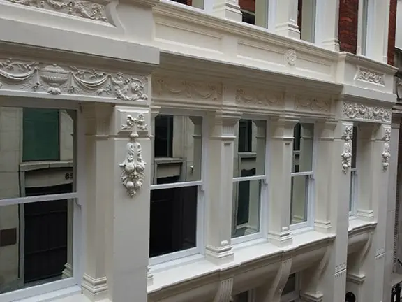Elegant white stone façade showcasing detailed architectural features, including ornate window frames and decorative elements, reflecting the expertise in stone restoration services offered by Environ Restoration.