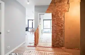 Interior renovation showcasing a partially restored wall with exposed brick, contrasting modern decor and flooring, highlighting the differences between restoration and renovation.