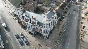 Aerial view of a historic building with ornate architecture, surrounded by urban streets and parked cars, illustrating the importance of brickwork restoration and maintenance.