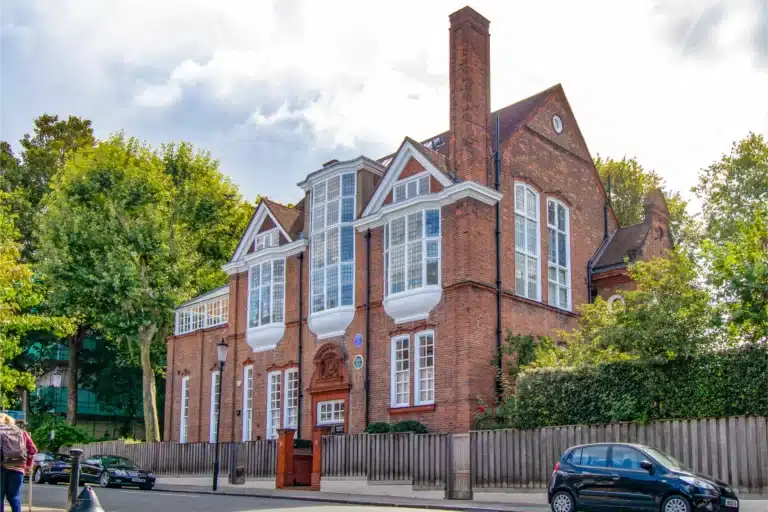 Edwardian-style building with large windows, detailed brickwork, and surrounding greenery, showcasing architectural restoration expertise by Environ Restoration Services.