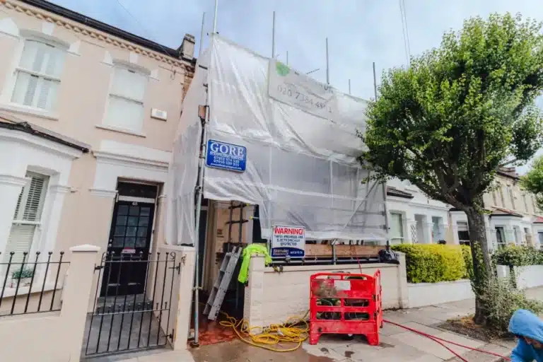 House undergoing restoration with scaffolding, protective sheeting, and construction signage, showcasing Environ Restoration Services' commitment to preserving London's architectural heritage.