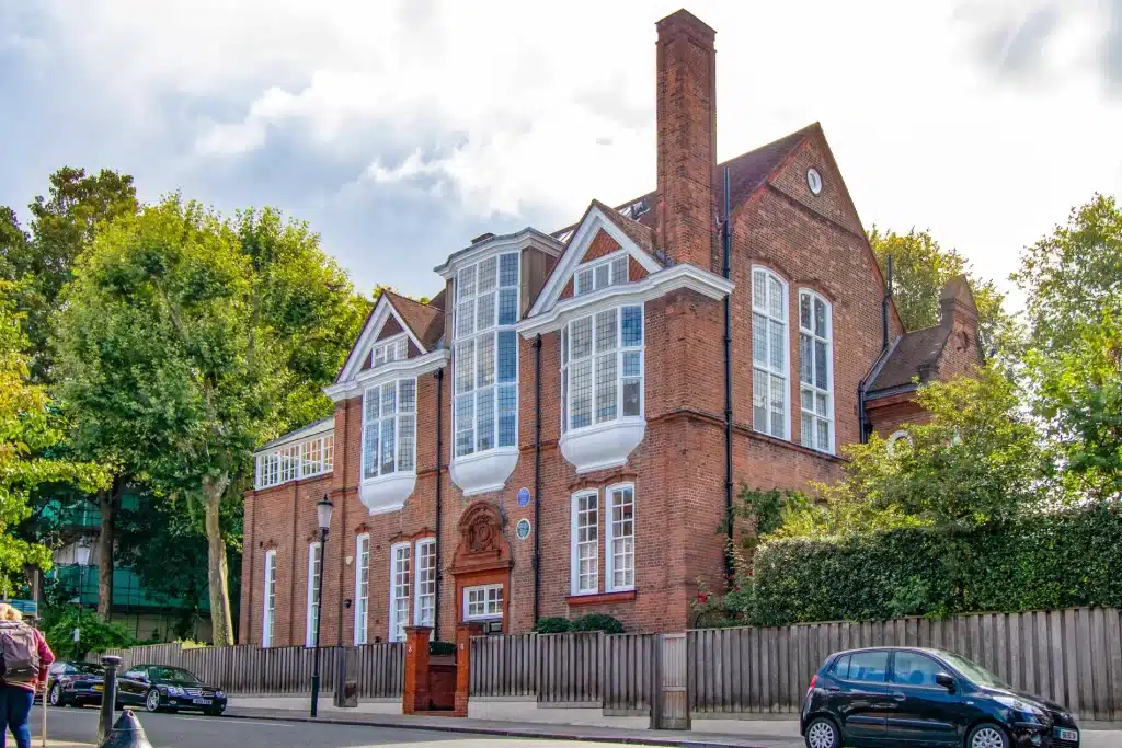 Edwardian-style property with intricate architectural features, large bay windows, and a red brick façade, surrounded by greenery, showcasing restoration potential for period homes.