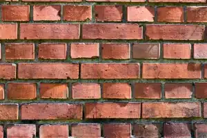 Close-up of a brick wall showing various shades of red and signs of weathering, relevant to DIY and professional brick cleaning discussions.