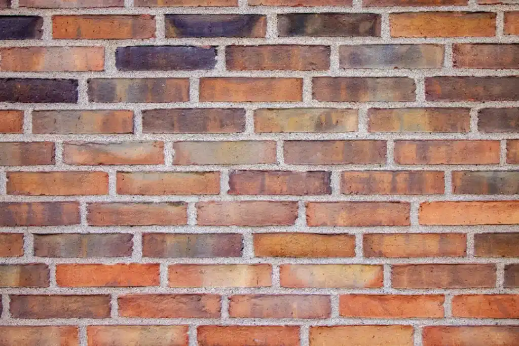 Brick wall showcasing various shades of red and brown, highlighting texture and mortar joints, relevant to brick cleaning and restoration services.