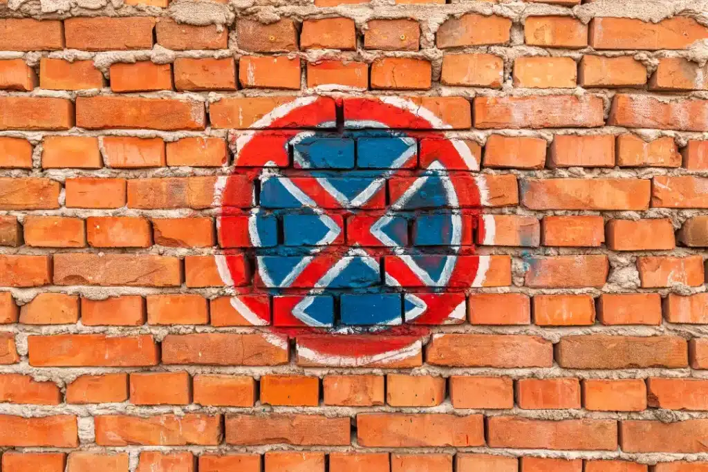 Graffiti symbol on brick wall, showcasing blue and red paint on a textured brick surface, relevant to techniques for graffiti removal from brick walls.